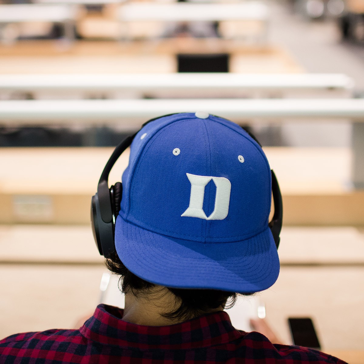 Photo of Student Wearing a Duke hat sitting in library