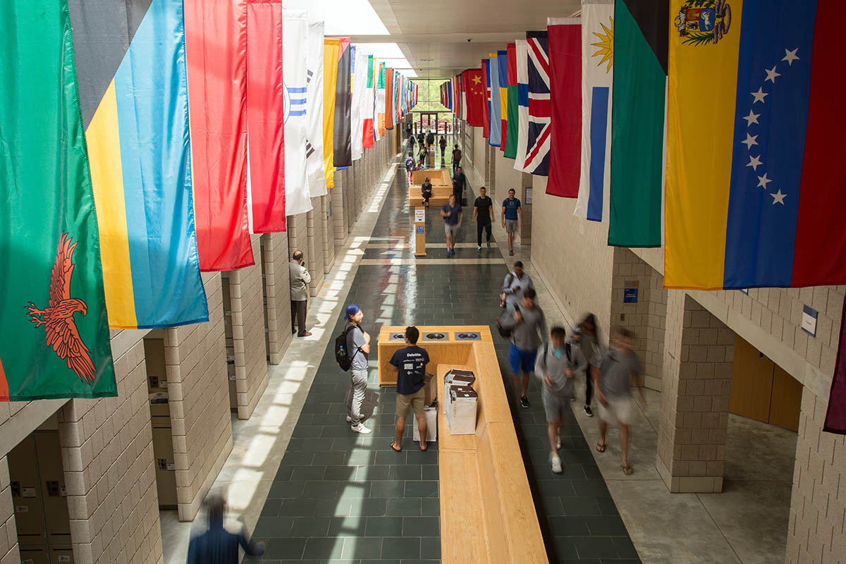 students walking in the hall lined with flags of various countries and other groups